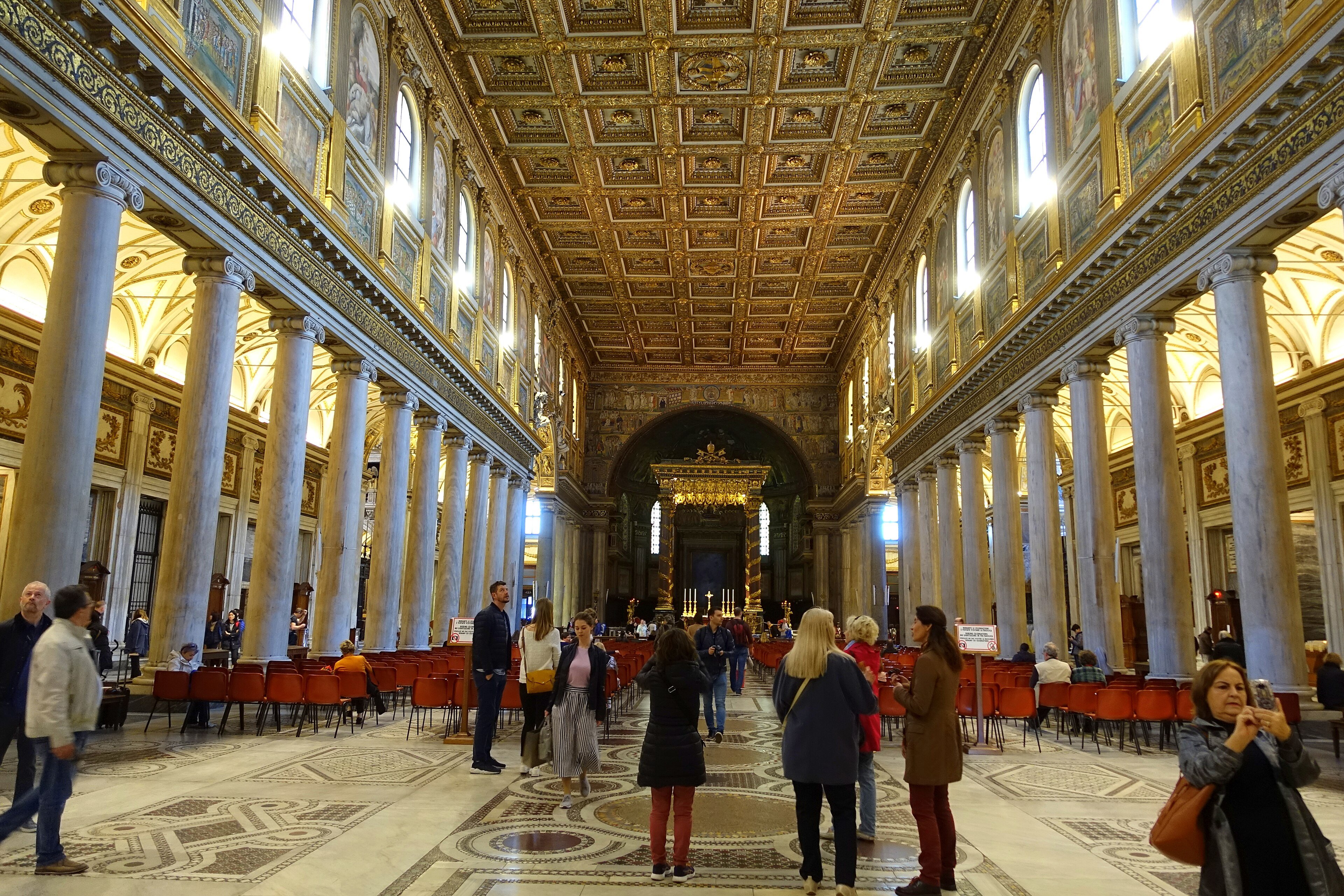 The long nave of Santa Maria Maggiore in Rome, lined with marble columns under a gilded coffered ceiling