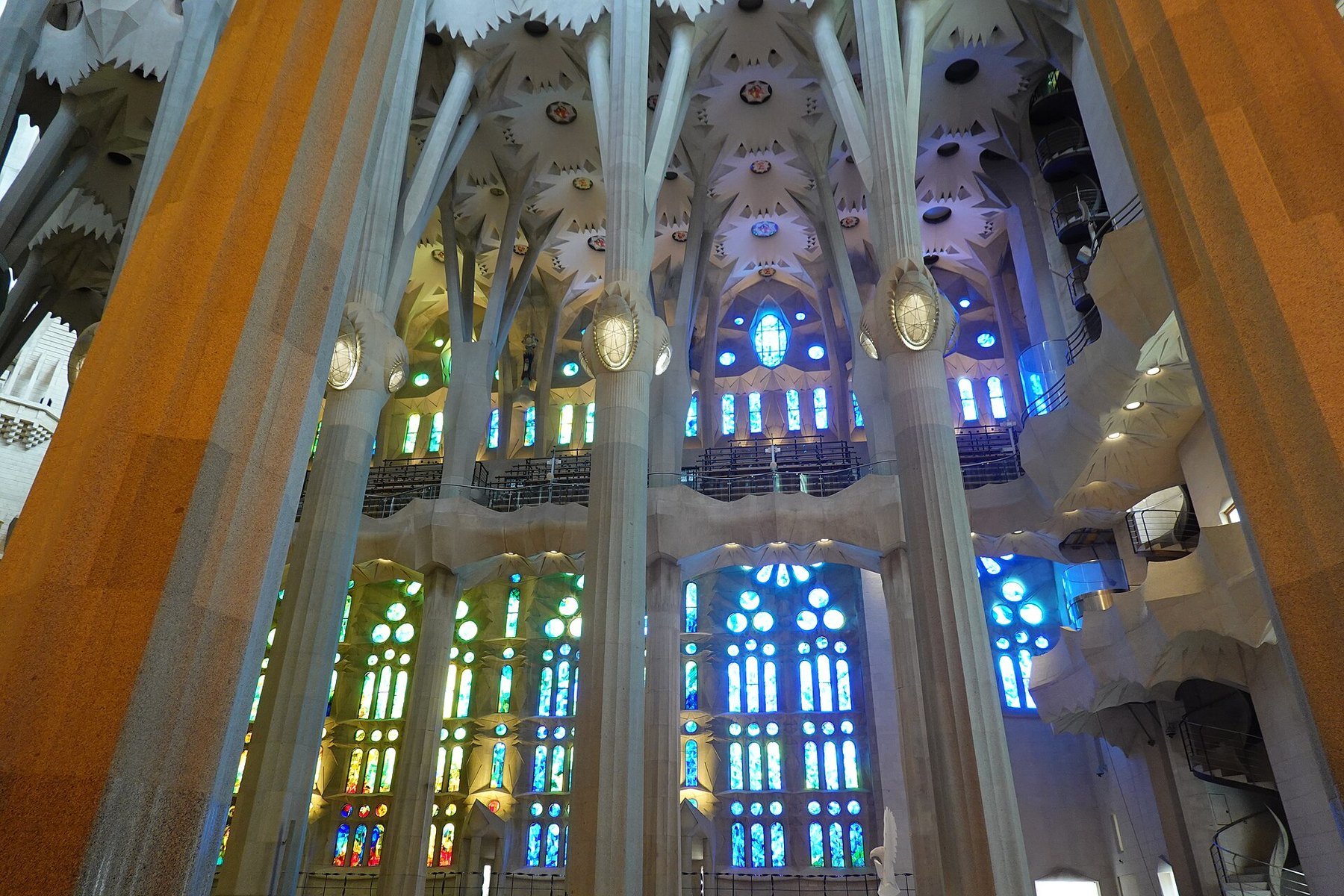 The nave of the Sagrada Família in Barcelona with tree-like columns and blue and green stained glass